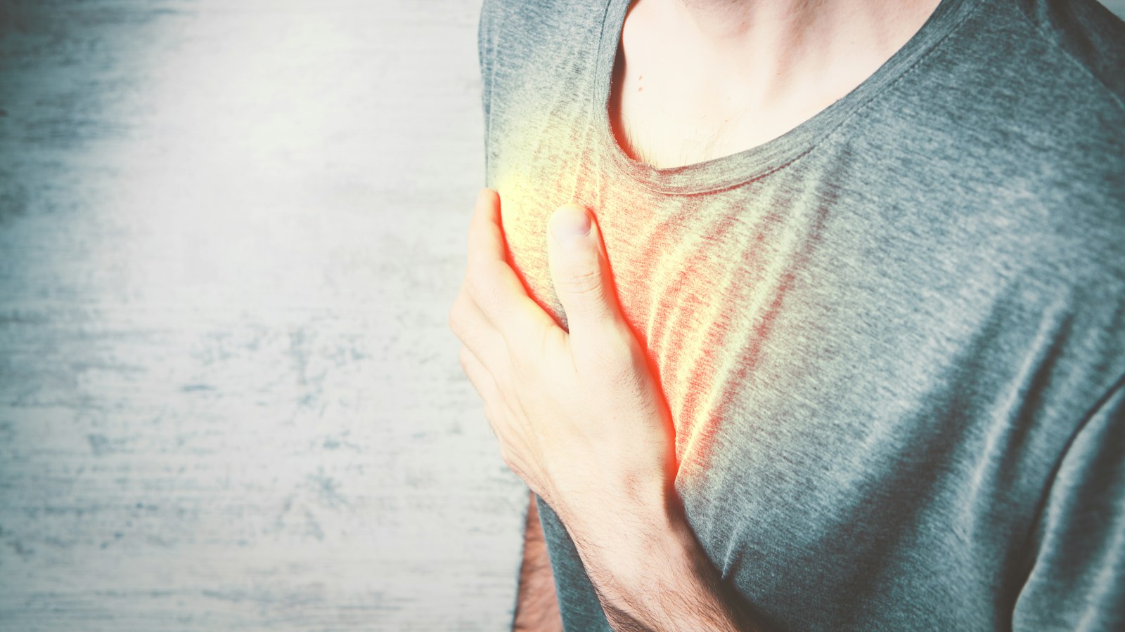 Man holding his chest in discomfort, a common heart attack warning sign